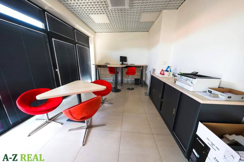 Kanceláře s červenými židlemi a počítačem, podlaha s dlažbou.