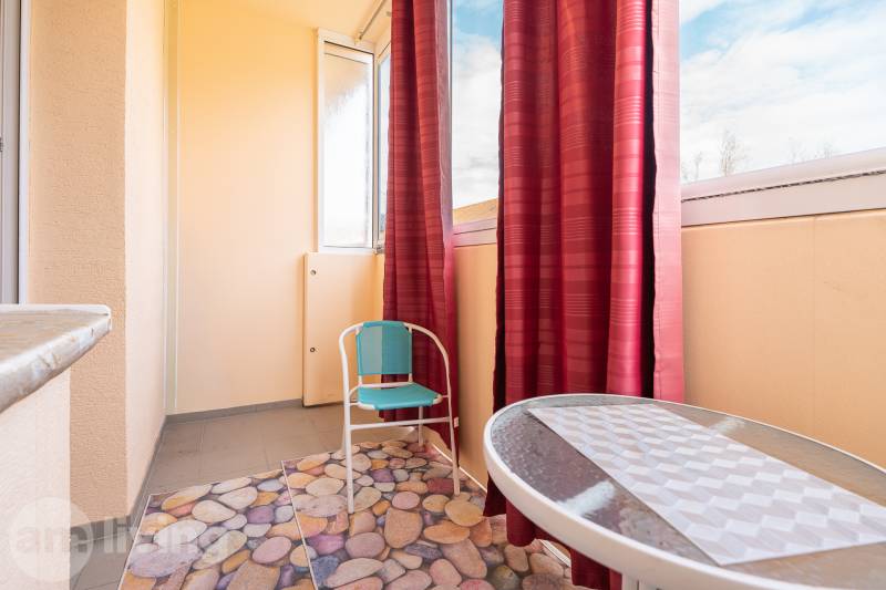 Zasklená lodžie s kobercem a židlí v 1-pokojovém bytě.