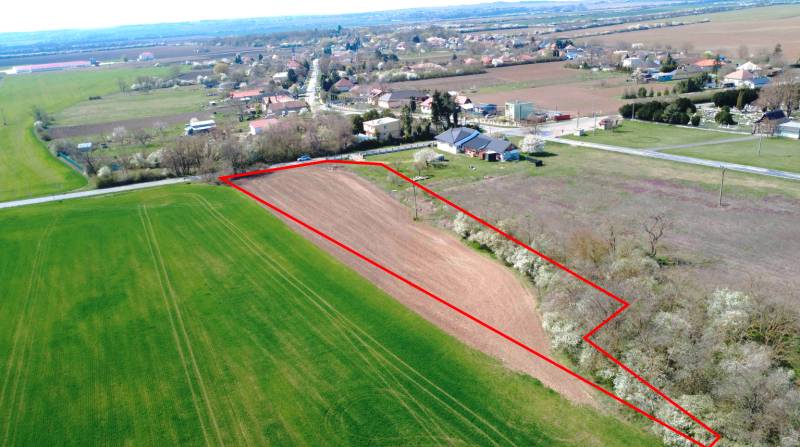 Letecký pohled na zemědělskou plochu v Ondřejovicích obklopenou zahradami a vesnicí.