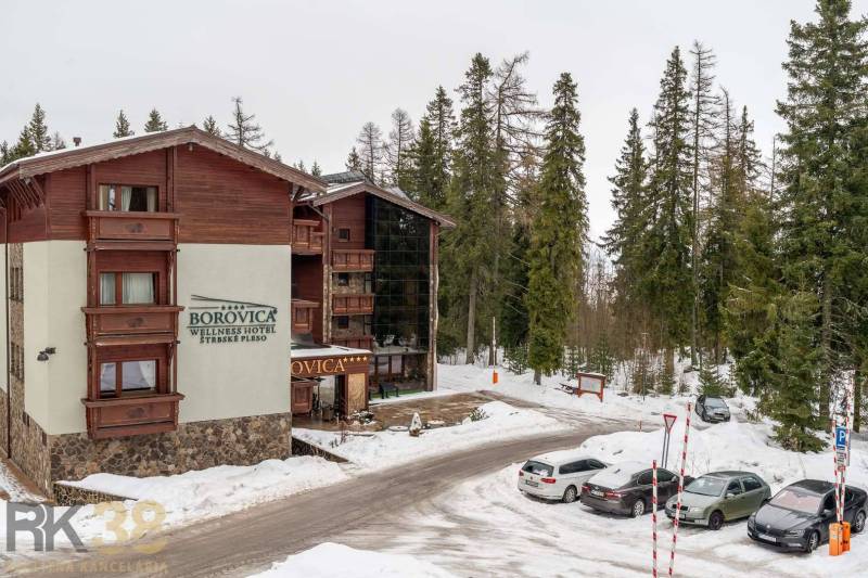 Rekreační apartmán v Popradu obklopený zasněženým lesem a parkovacím prostorem.