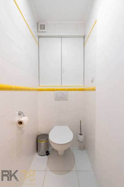 Koupelna s bílými kachličkami a žlutými detaily v Rekreačním apartmánu.