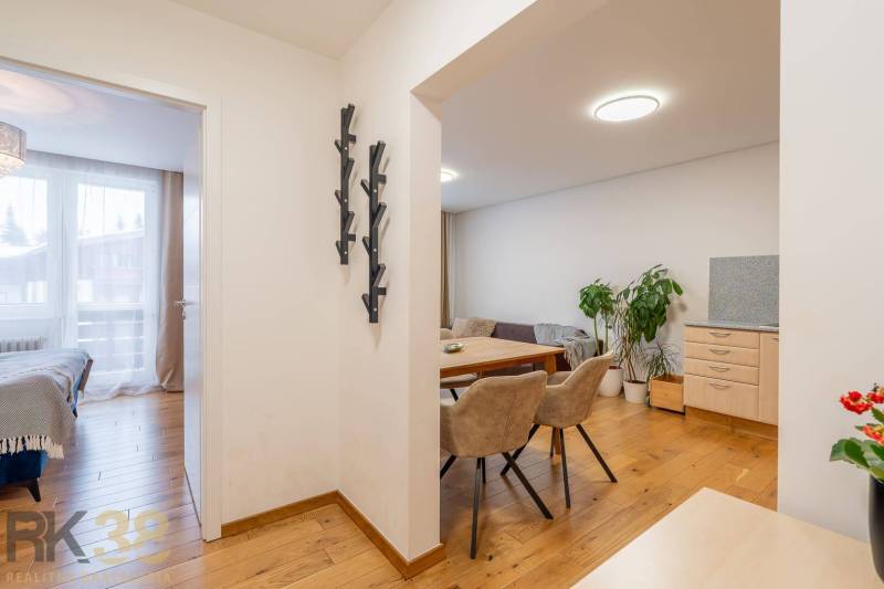 Interiér rekreačního apartmánu s podlahou s dřevěným dekorem, jídelnou a ložnicí.