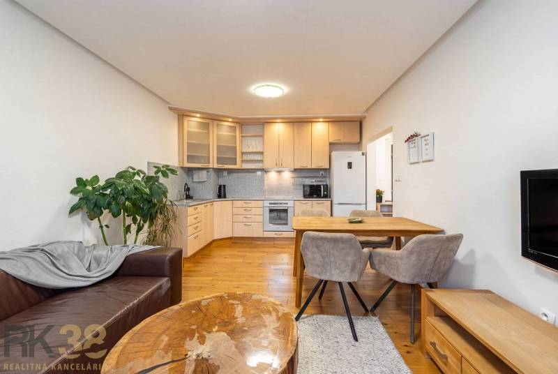 Obývací pokoj s kuchyňským koutem v rekreačním apartmánu a podlahou s dřevěným dekorem.