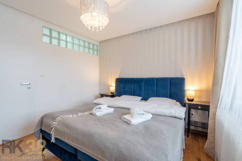 Ložnice v rekreačním apartmánu s manželskou postelí a podlahou s dřevěným dekorem.