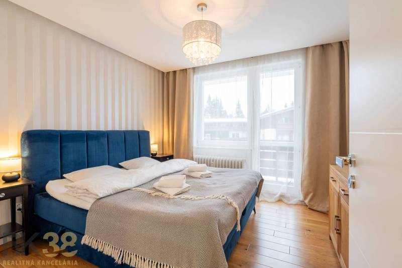 Ložnice v rekreačním apartmánu s pohodlnou postelí a podlahou s dřevěným dekorem.