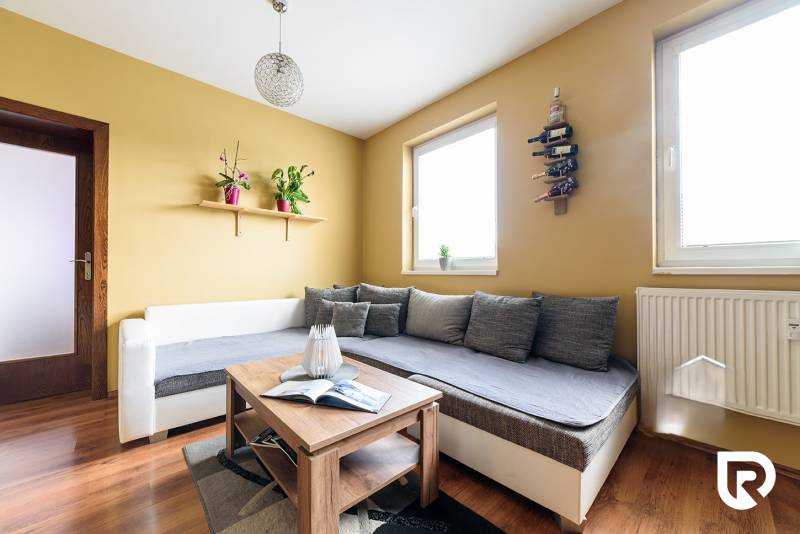 Obývací pokoj v 2-pokojovém bytě s podlahou s dřevěným dekorem a pohodlným sezením.