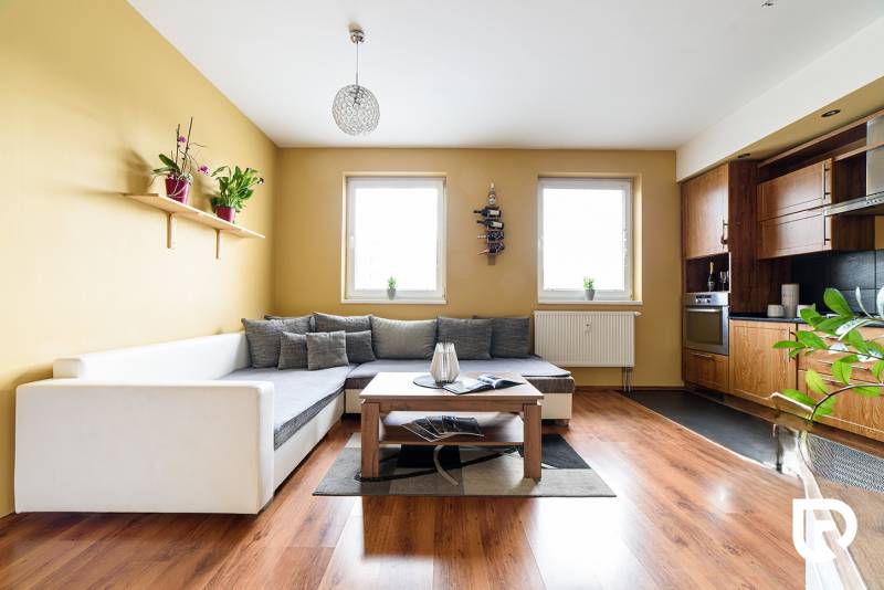 Obývací pokoj v 2pokojovém bytě s kuchyní a podlahou s dřevěným dekorem.