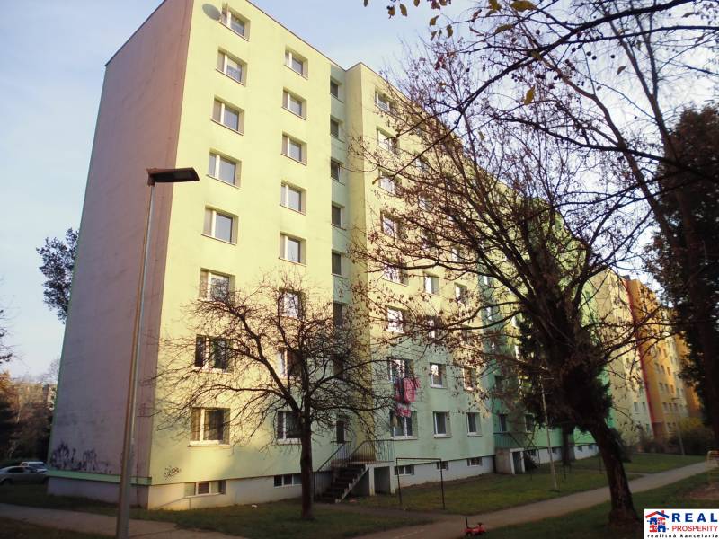 Bytový dům v Prešově s chodníkem a stromy.