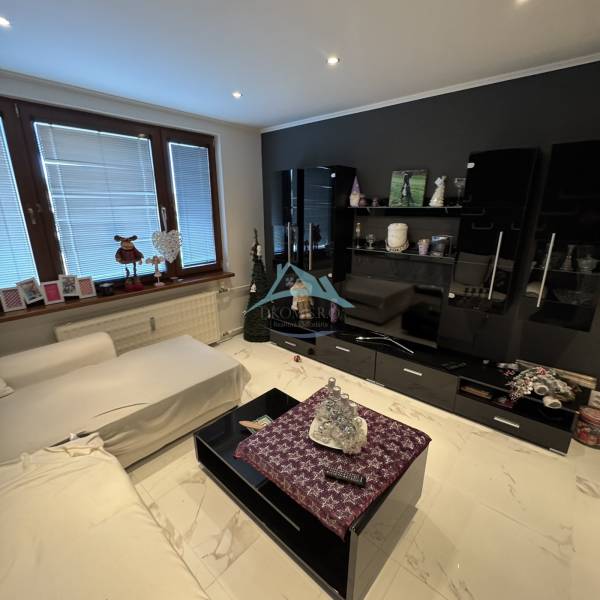 Obývací pokoj ve 2-pokojovém bytě s moderním nábytkem a dlažbou na podlaze.