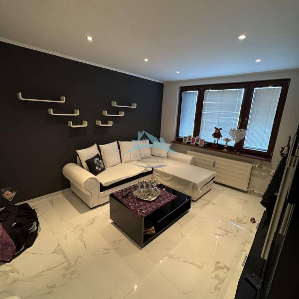 Obývací pokoj v 2-pokojovém bytě s tmavou stěnou a moderním zařízením.