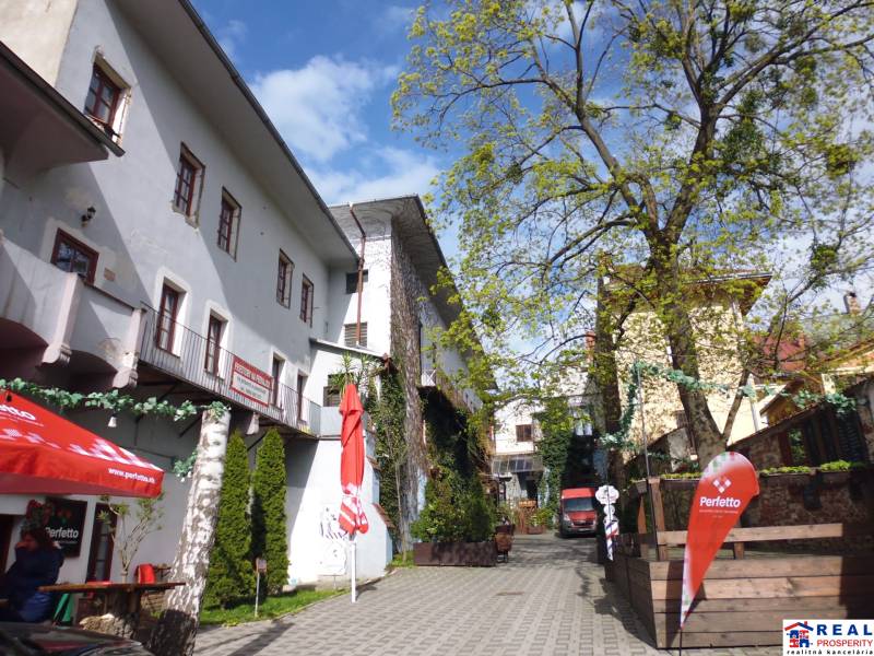 Úzký dvůr s třípatrovými budovami a kavárenskými židlemi na Hlavní ulici v Prešově.
