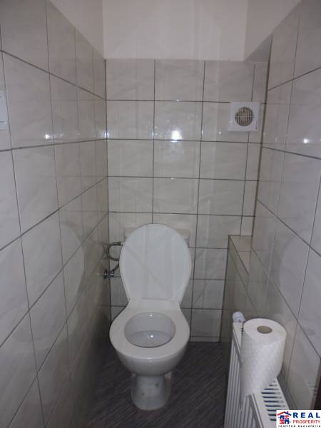 Toaleta v 3-pokojovém bytě s dlažbou a ventilačním otvorem.