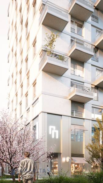 Bytový dům na Mlynských nivách v Bratislavě - Ružinově s balkony a rozkvetlými stromy.