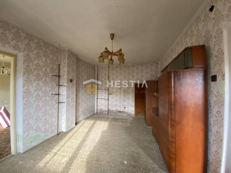 Interiér rodinného domu s retro tapetami a dřevěnou obývací stěnou.