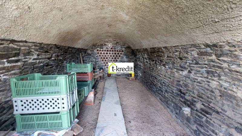 Kamenný sklep s regály a plastovými bednami ve Vinicích.
