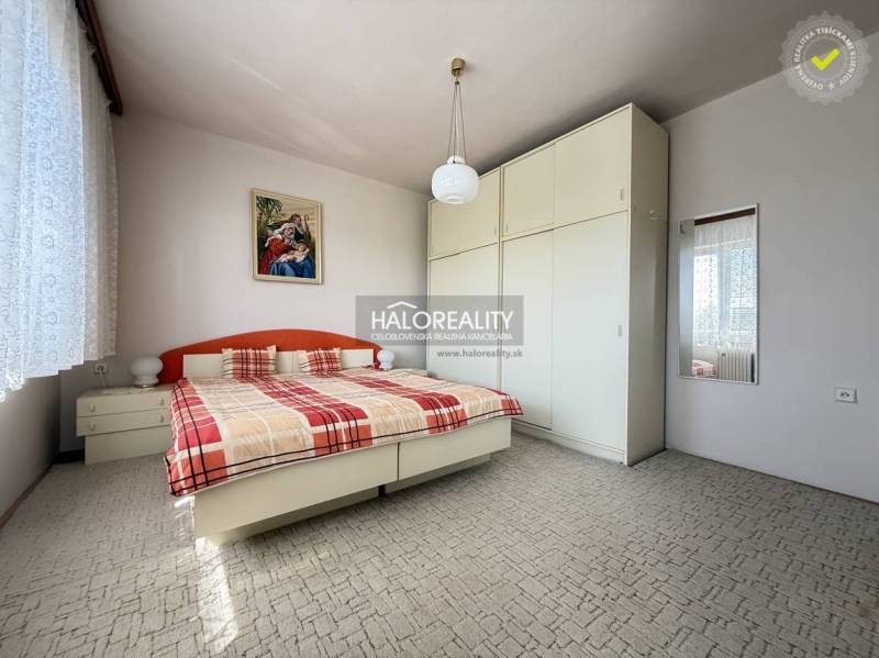 Ložnice v rodinném domě s velkou skříní, postelí a obrazem na stěně.