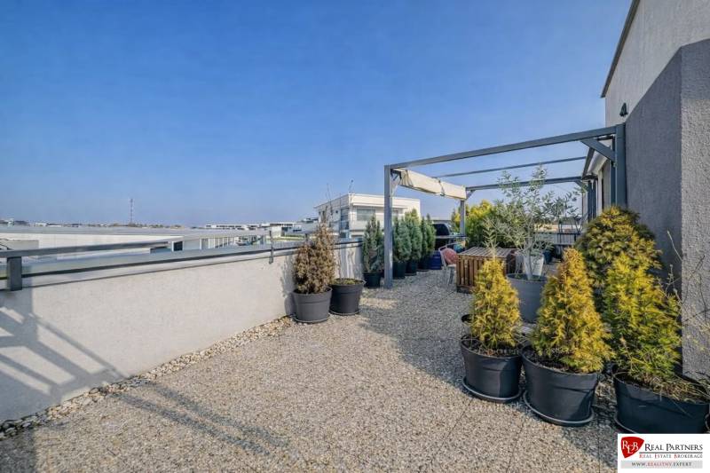 Střešní terasa 2pokojového bytu na Orechové ulici v Dunajské Lužné s rostlinami v květináčích.