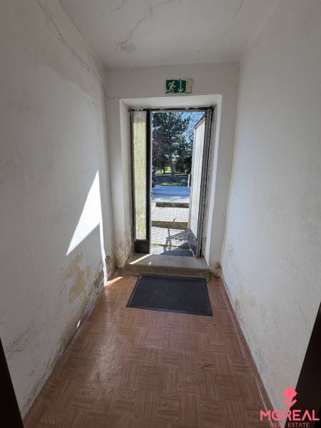Chodba se staršími stěnami a podlahou s dřevěným dekorem v rodinném domě.