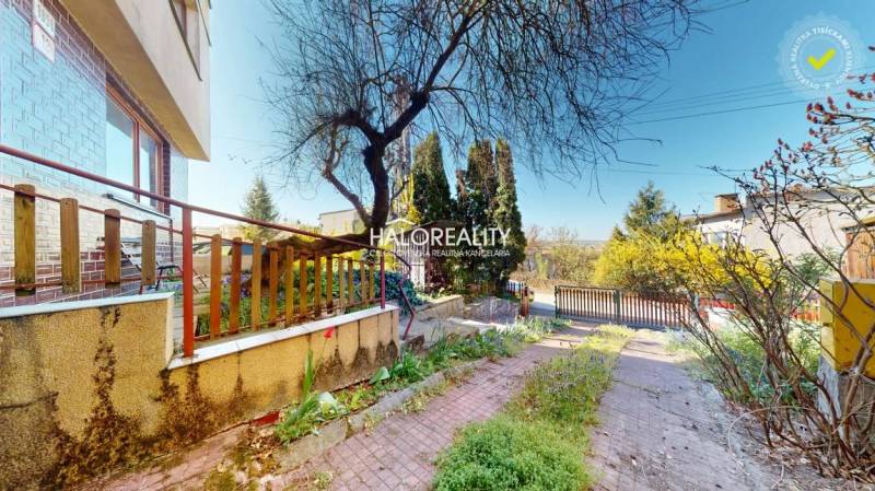 Rodinný dům v Rimavské Sobotě s dvorem, stromy a dlážděným chodníkem.