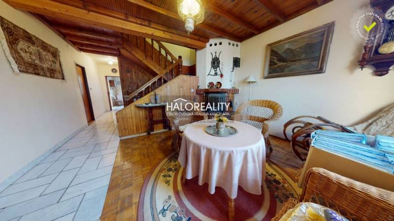 Rodinný dům s podlahou s dřevěným dekorem, ratanový nábytek, krb, koberec, dřevěný strop.