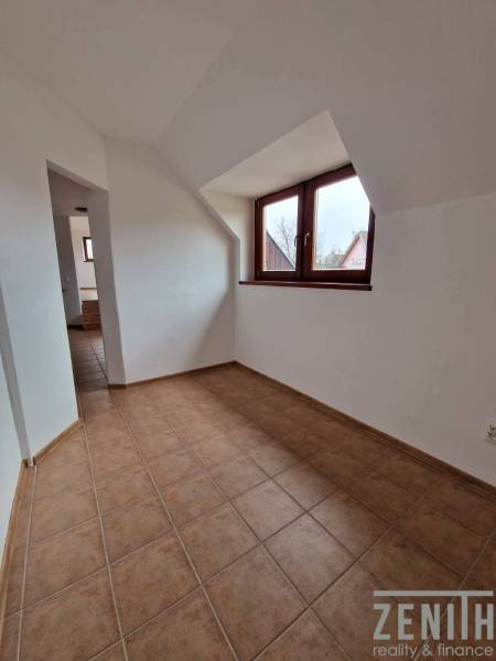 Interiér obchodních prostor s keramickou podlahou a šikmým stropem.