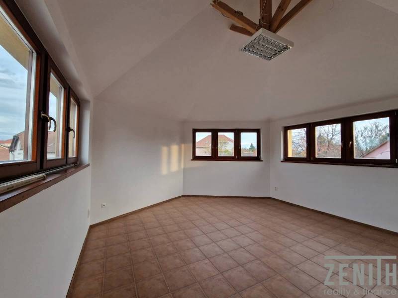 Interiér obchodních prostor s dlažbou a velkými okny, poskytující dostatek denního světla.