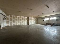 Výrobní prostory s vysokým stropem a betonovou podlahou.