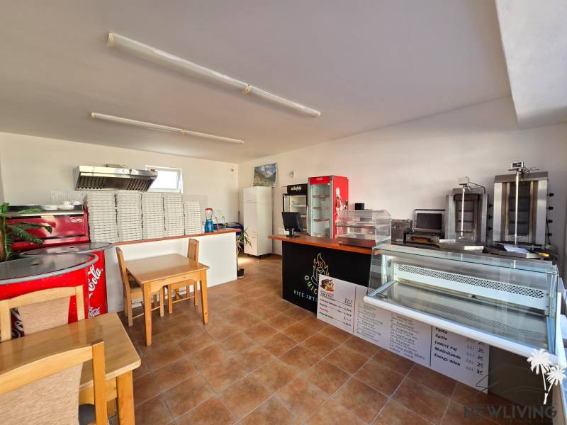 Interiér gastro prostor s pultem, chladicími vitrínami a stoh krabic na pizzu.