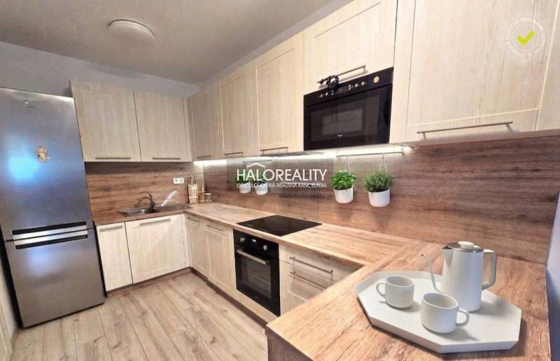 Moderní kuchyně v 2pokojovém bytě s dřevěným dekorem a vestavěnými spotřebiči.