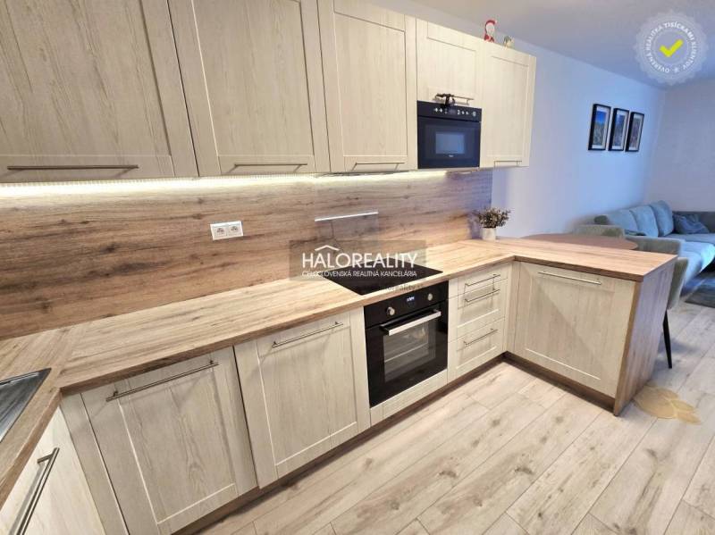 Kuchyně s podlahou s dřevěným dekorem v 2-pokojovém bytě, světlé dřevěné skříňky a vestavěné spotřebiče.