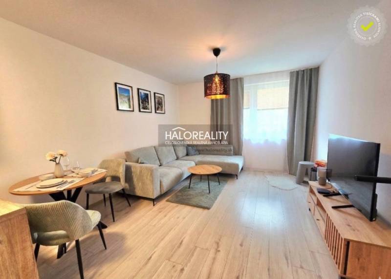 Obývací pokoj v 2-pokojovém bytě s rohovou sedačkou a televizorem, podlaha s dřevěným dekorem.