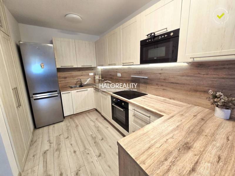 Kuchyně v 2-pokojovém bytě s podlahou s dřevěným dekorem a světlým nábytkem.