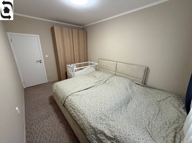 Ložnice s šedou postelí, dětskou postýlkou a šatní skříní ve 4pokojovém bytě.