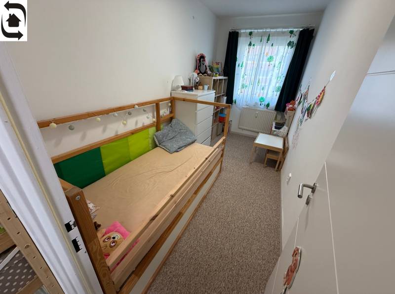 Dětský pokoj ve 4-pokojovém bytě s postelí, komodou a barevnými závěsy.