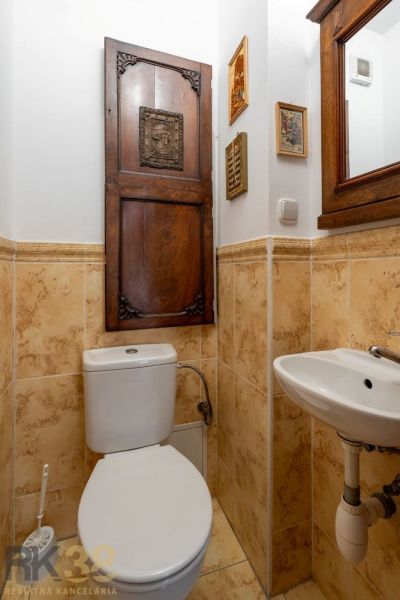 WC s dřevěnými dveřmi a zrcadlem, keramické obklady, umyvadlo ve 4-pokojovém bytě.