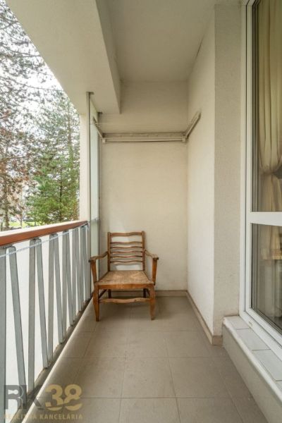 Balkon s dřevěnou židlí a zábradlím ve 4-pokojovém bytě.