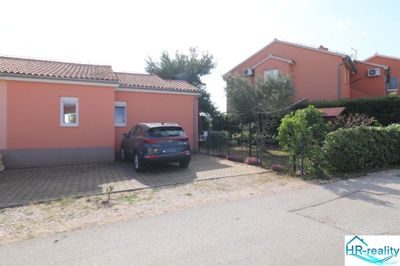 Rodinný dům ve městě Vodice, parkovací místo a zahrada s květinami a stromy.