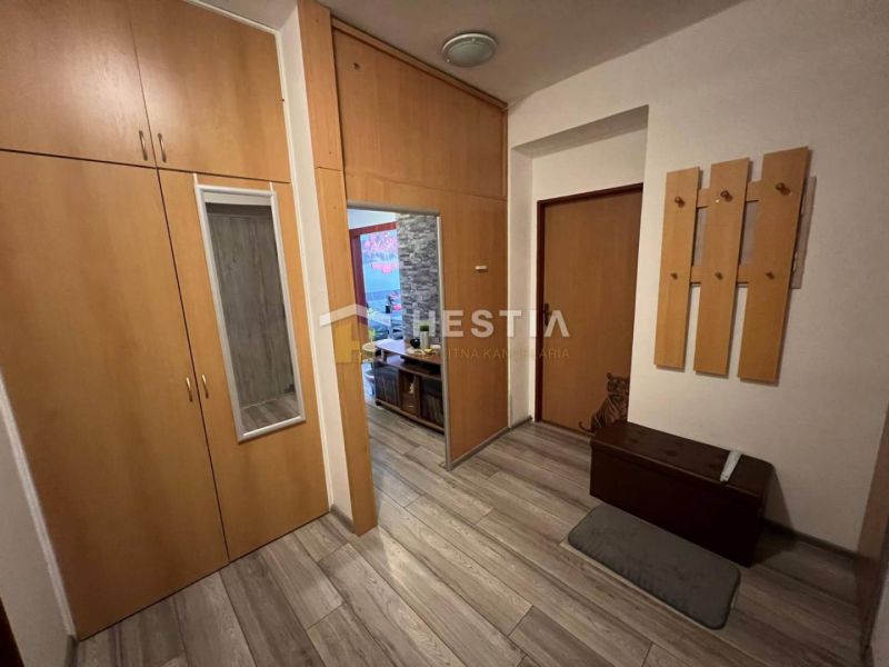 Předsíň v 3-pokojovém bytě s dřevěným dekorem a vestavěnými skříněmi.