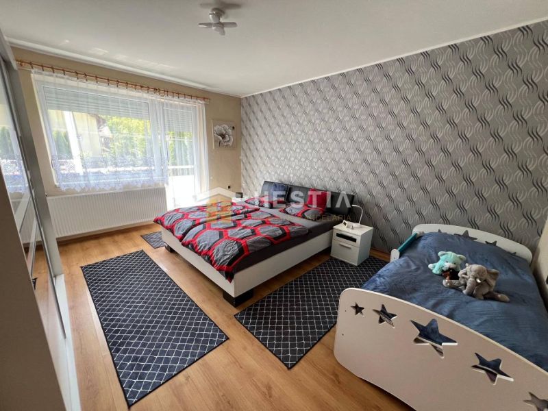 Ložnice s manželskou postelí, dětskou postelí a podlahou s dřevěným dekorem v 3-pokojovém bytě.