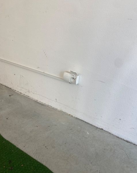 Bílá stěna se zásuvkou a betonová podlaha v garážích na Kazanské ulici.