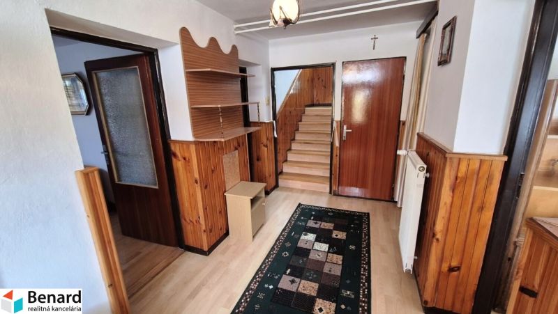 Interiér s dřevěným obkladem, podlaha s dřevěným dekorem, schody, koberec a nábytek.