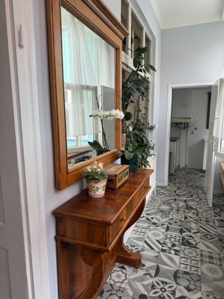 Dřevěná komoda s květinami a zrcadlem, designovaná dlažba na podlaze.