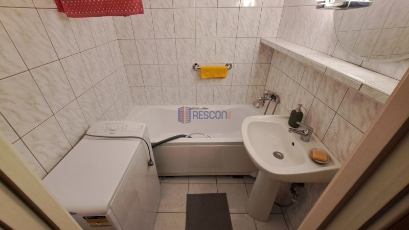Koupelna se sprchovým koutem, pračkou a umyvadlem v 2-pokojovém bytě.