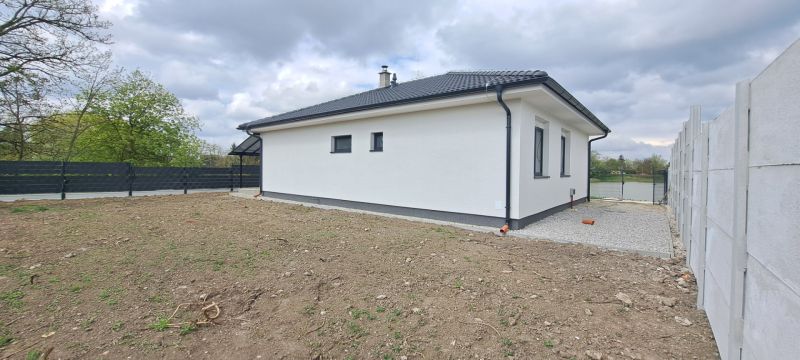 Rodinný dům v Selicích se zahradou a betonovým plotem za oblačného počasí.