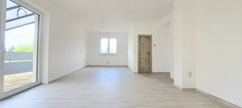 Interiér rodinného domu s oknem a podlahou s dřevěným dekorem.