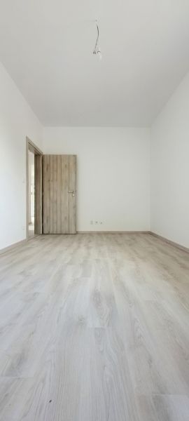Pokoj s podlahou s dřevěným dekorem a dřevěnými dveřmi v rodinném domě.