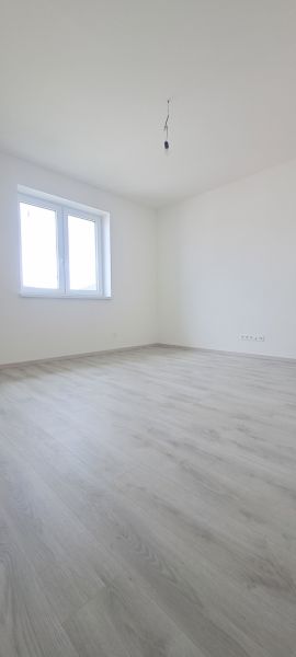 Prázdná místnost s bílými stěnami a podlahou s dřevěným dekorem v rodinném domě.