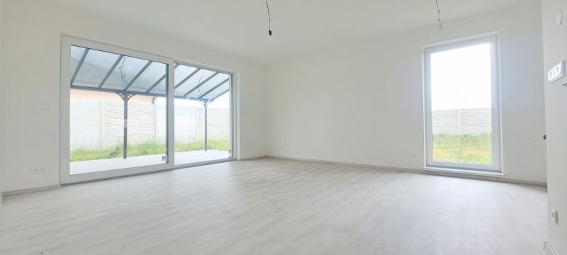 Prostorný pokoj s velkými okny a podlahou s dřevěným dekorem v rodinném domě.