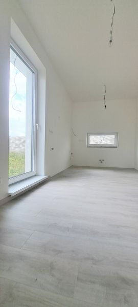 Interiér rodinného domu s podlahou s dřevěným dekorem a velkým oknem.