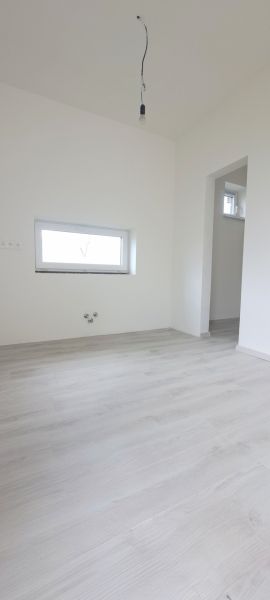 Pokoj v rodinném domě s podlahou s dřevěným dekorem a malým oknem.